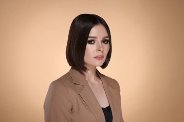 Bej arka planda harika düz saçları olan güzel bir genç kadının portresi.