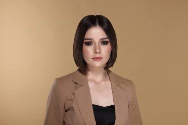 Bej arka planda harika düz saçları olan güzel bir genç kadının portresi.