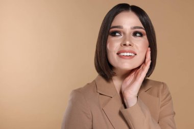 Güzel, genç ve mutlu bir kadının portresi. Bej arka planda harika düz saçları var. Mesaj atmak için yer var.