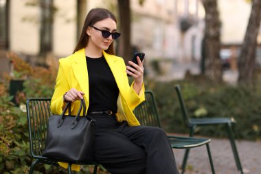 Açık havada akıllı telefonları olan şık takım elbiseli bir iş kadını. Metin için boşluk
