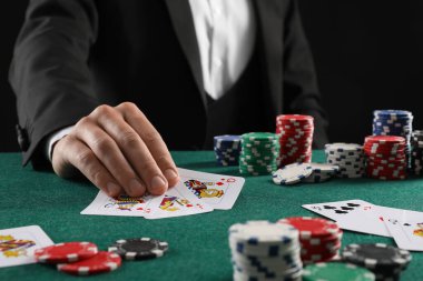Kumar masasında poker oynayan kart ve kumarhane fişleri olan adam, yakın plan.
