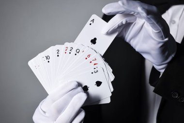 Gri arkaplanda oyun kartları olan illüzyonist, yakın plan