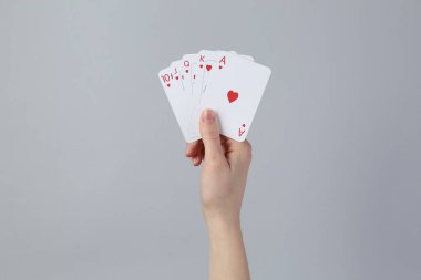 Gri arkaplanda kart oynayan kadın, yakın plan