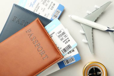 Biletli pasaportlar, uçak modeli ve arka planda pusula, düz konum
