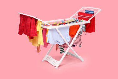 Açık pembe arka planda temiz çamaşırlı kuru askı.