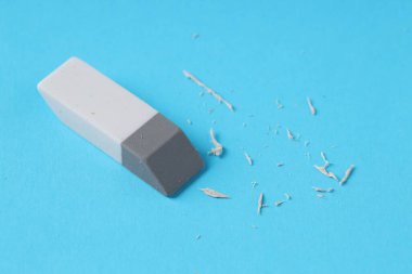 Açık mavi arkaplanda bir silgi ve kırıntılar, yakın plan.