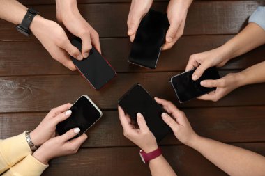 İnternet bağımlılığı. Ahşap masada akıllı telefonları olan insanlar.