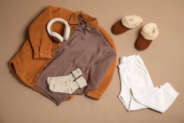 Şık kıyafetler, botlar ve bej arka planda aksesuarlar, düz yatış