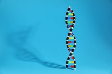 Açık mavi arka planda renkli DNA yapısı modeli. Metin için boşluk