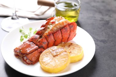 Lezzetli ıstakoz kuyruğu, mikro yeşillikler ve limon dilimleri gri desenli masa, yakın plan.