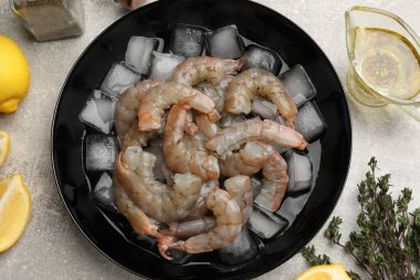 Taze çiğ karidesler kasede buz küpleri, baharatlar ve limonlar gri masada, düz yatıyordu.