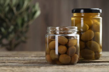 Ahşap masada cam kavanozlarda zeytin turşusu, yakın plan. Metin için boşluk
