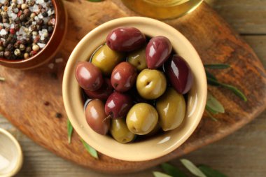 Tabakta lezzetli zeytinler, ahşap masada yapraklar ve baharatlar.