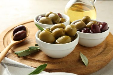 Lezzetli marine edilmiş zeytinler kaseler, kaşık, yağ ve yeşil yapraklar masada, yakın çekim