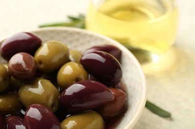 Lezzetli zeytinler kasede ve yağlar bej masada, yakın plan.
