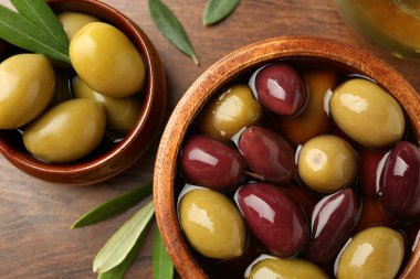 Lezzetli zeytinyağı, yağ ve yapraklar ahşap masada, düz yerde.