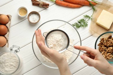 Havuçlu kek yapıyorum. Beyaz ahşap masada un karıştıran bir kadın.