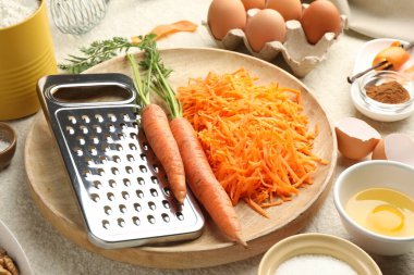 Bej desenli masada havuçlu kek yapmak için farklı malzemeler.