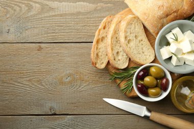 Ahşap masada servis edilen lezzetli marine edilmiş zeytin, ekmek ve peynir, üst manzara. Metin için boşluk