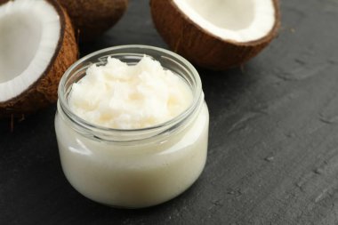 Cam kavanozda pişen organik hindistan cevizi yağı ve siyah masada taze meyveler, yakın plan. Metin için boşluk