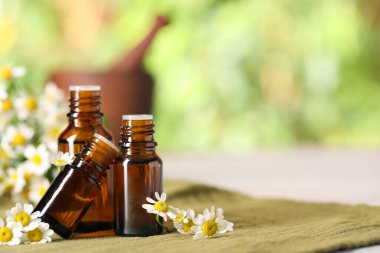 Gerekli yağ şişeleri ve kumaş üzerinde papatya çiçekleri. Metin için boşluk