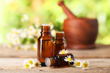 Esans ve ahşap masaya papatya çiçek şişe