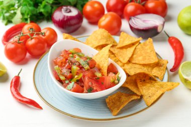 Lezzetli salsa (Pico de gallo) nachos ve malzemelerle servis edilir beyaz ahşap masa üzerinde, yakın çekim
