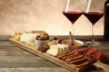 Farklı lezzetli peynir çeşitleri, diğer atıştırmalıklar ve şarap ahşap masada, yakın plan.