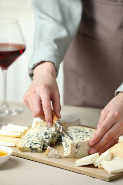 Açık renkli masada leziz peynirleri doğramış bir kadın, yakın plan.
