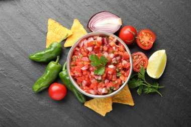 Kasede leziz salsa sosu, cipsler ve malzemeler gri masada, düz yerde.