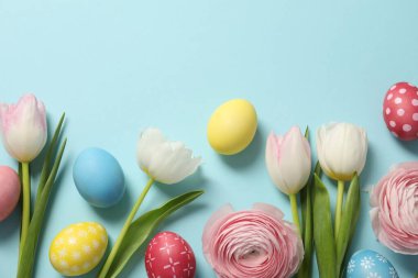 Paskalya yumurtaları ve açık mavi arka planda güzel bahar çiçekleri. Metin için boşluk