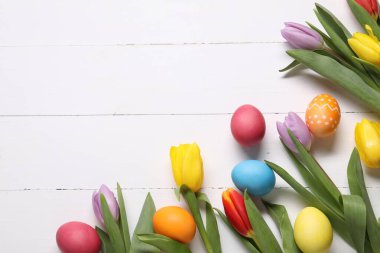 Paskalya yumurtaları ve beyaz ahşap arka planda güzel laleler. Metin için boşluk
