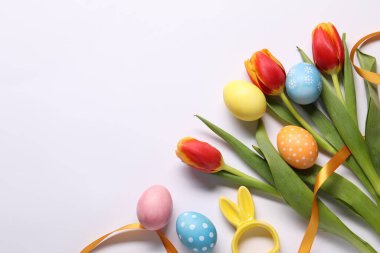 Paskalya yumurtaları, güzel laleler ve beyaz arka planda tavşan figürü. Metin için boşluk