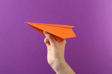 Mor arka planda turuncu kağıt uçaklı kadın, yakın plan.