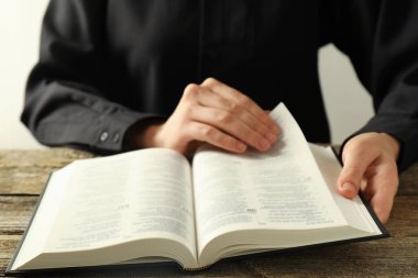 Kutsal kitabı İngilizce okuyan kadın ahşap masada, yakın plan.