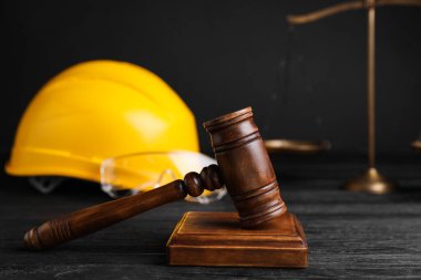 İş yerinde kaza oldu. Gavel, pullar ve inşaat işçilerinin koruyucu giysileri siyah ahşap masada, seçici odaklı.