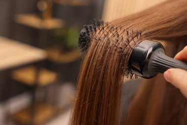 Kuaför, kuaför kuaförü kuaföründe müşterinin saçını tarıyor.