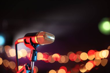 Karanlık arka planda duran bulanık ışıklı mikrofon, mesaj için yer var. Bokeh etkisi