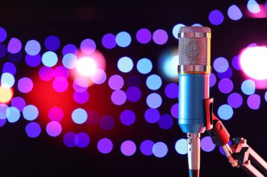 Karanlık arka planda duran bulanık ışıklı mikrofon, mesaj için yer var. Bokeh etkisi