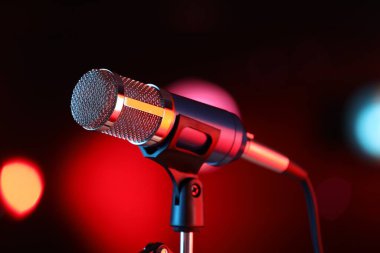 Mikrofon kırmızı arka planda bulanık ışıklarla duruyor. Bokeh etkisi