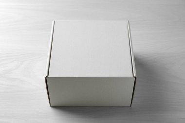 Beyaz ahşap arka planda boş bir karton kutu. Tasarım için model