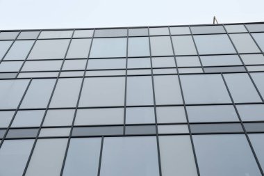 Mavi gökyüzüne karşı birçok penceresi olan modern bina, düşük açı görünümü