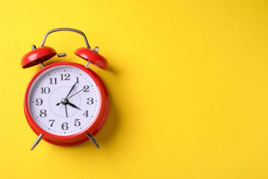 Sarı arka planda kırmızı alarm saati, üst manzara. Metin için boşluk