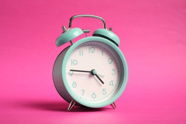 Parlak pembe arka planda bir turkuaz alarm saati