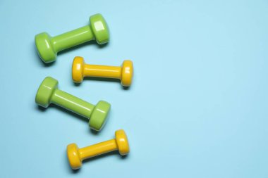 Açık mavi arka planda dambıllar, düz yatış. Metin için boşluk