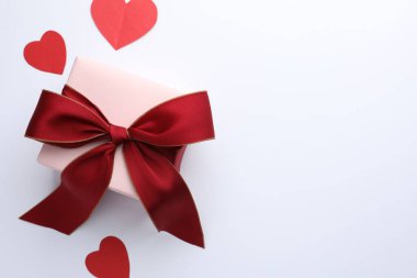 Kırmızı fiyonklu hediye kutusu ve beyaz arka planda kağıt kalpler, düz yatıyordu. Metin için boşluk