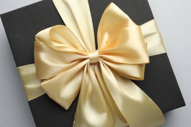 Açık gri arka planda altın fiyonklu hediye kutusu, üst görünüm