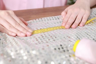 Masada çalışan bantlı ve parlak kumaşlı kadın, yakın plan.