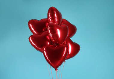 Açık mavi arka planda bir sürü kırmızı kalp şeklinde balon. Sevgililer Günün kutlu olsun.