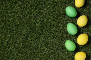 Yeşil çimlerin üzerinde güzel süslü Paskalya yumurtaları, düzlük. Metin için boşluk